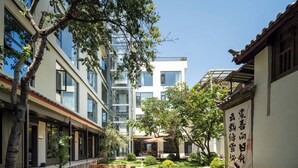 A courtyard with a mix of modern and traditional architecture, including a building with large windows and a traditional structure with a tiled roof. - Lijiang Ancient City Hitone Resort (Lijiang)