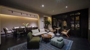 A modern lounge area with a sofa, chairs, a coffee table, and a patterned rug. - Lijiang Ancient City Hitone Resort (Lijiang)