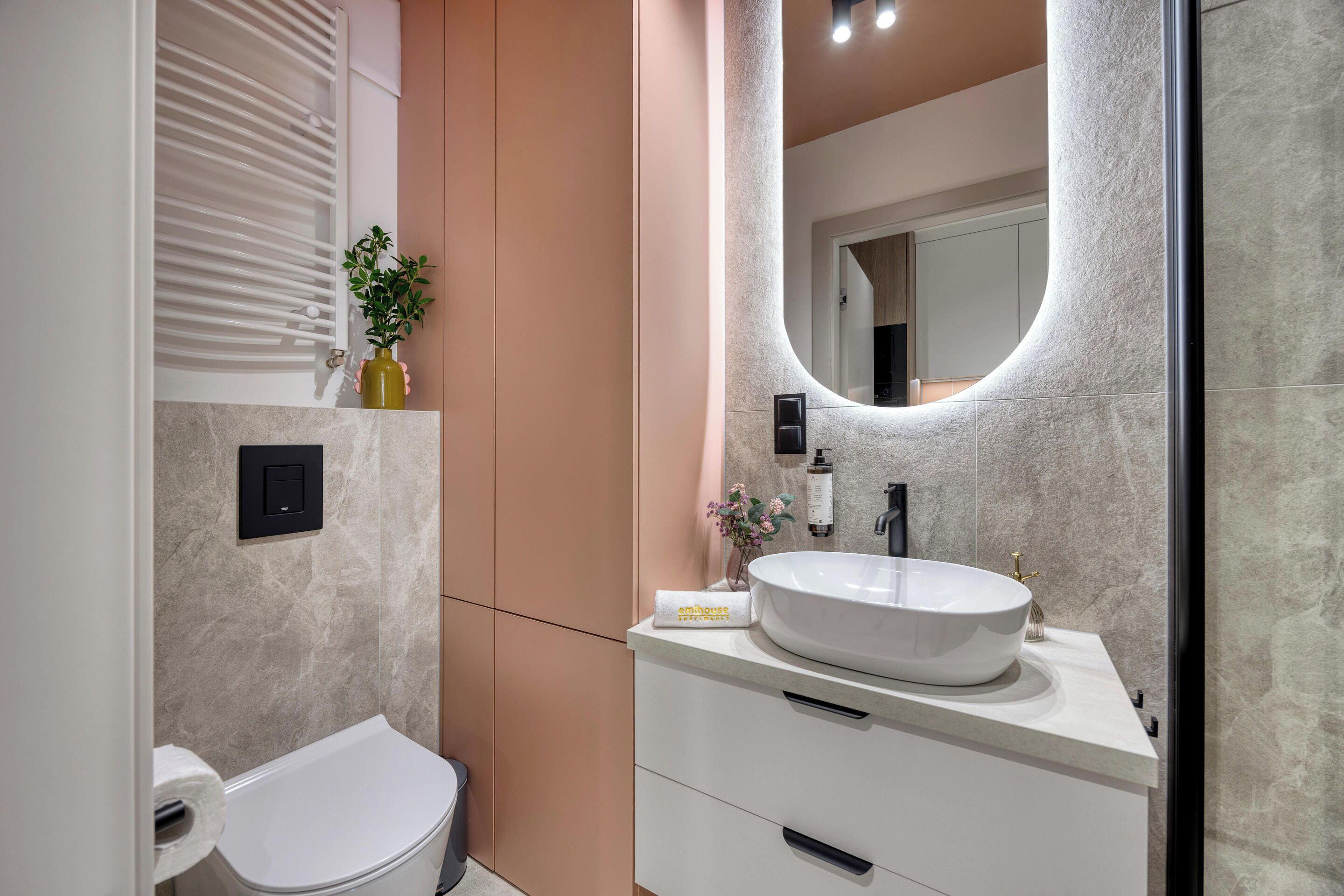 Un baño moderno con un inodoro blanco, un lavabo redondo grande y un espejo.