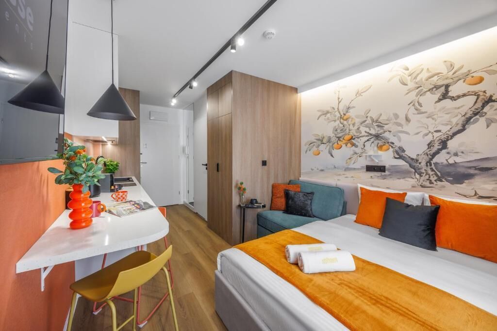 A modern hotel room with a bed, a desk, and a dining area.