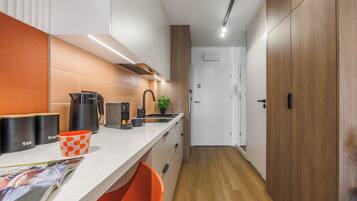 Una cocina moderna con encimera blanca, cafetera, hervidor y lavabo.