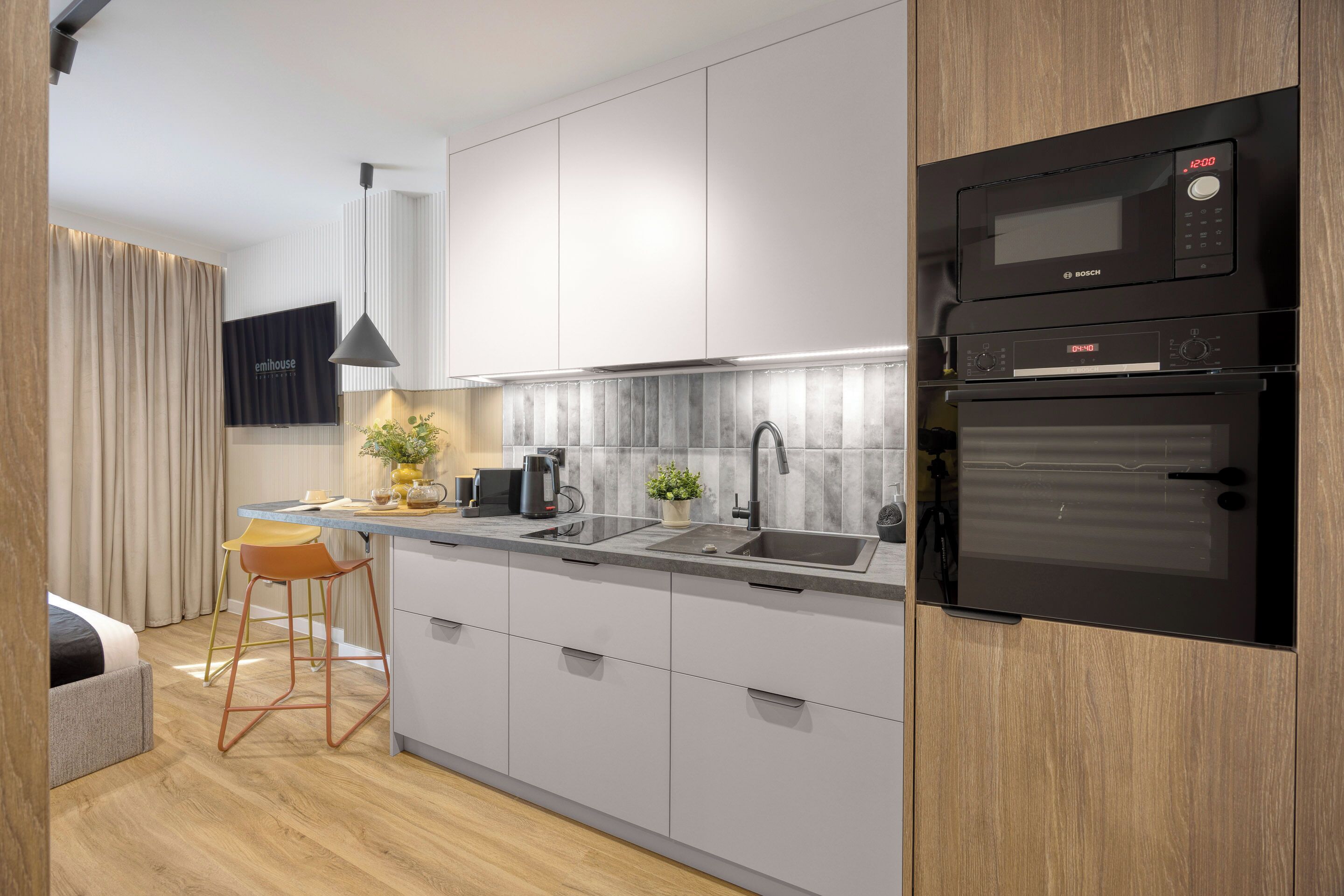 Una cocina moderna con microondas y horno integrados de Bosch, un lavamanos y un taburete de bar.