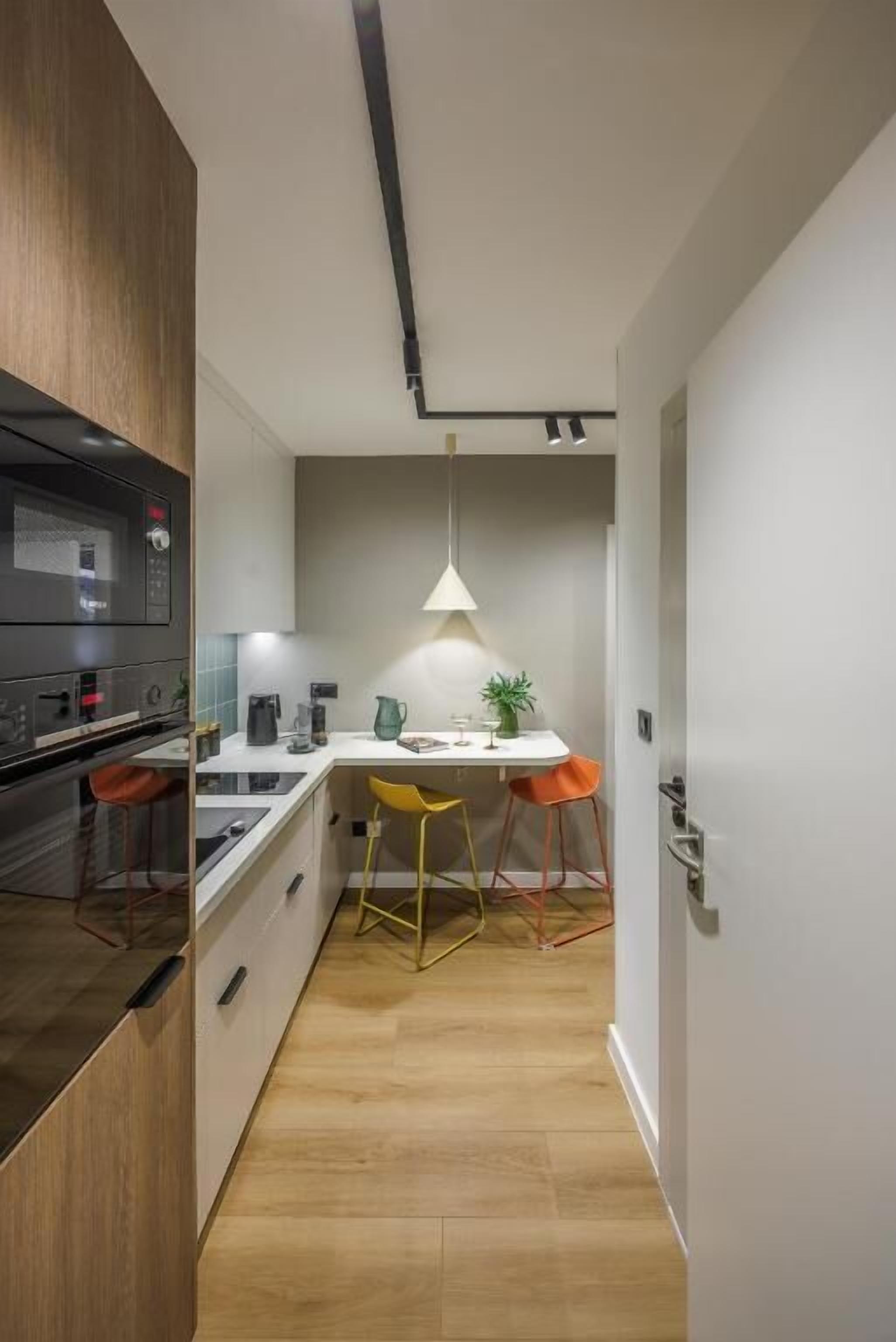 Una cocina moderna con una isla central, un horno empotrado y una lámpara colgante sobre la isla.