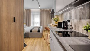 A modern kitchen with a built-in stove, a coffee machine, and a bar area. - Emihouse Rubikon Apartments (Rzeszów)