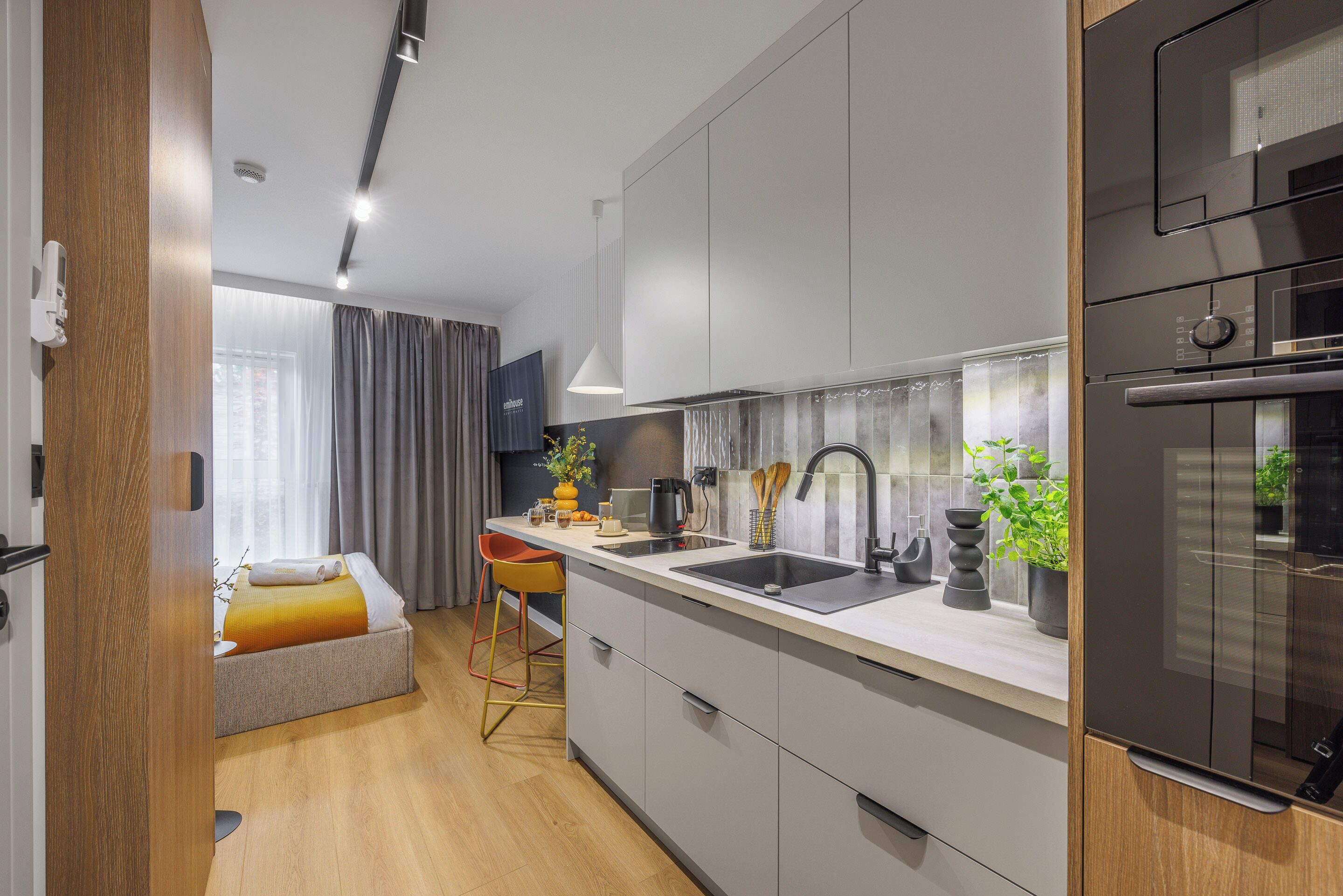 A modern kitchen with a built-in oven, a sink, and a dining area with a chair and table.
