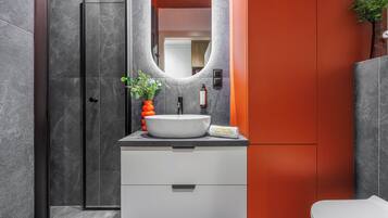 Une salle de bain moderne avec un lavabo blanc, un miroir et une douche.
