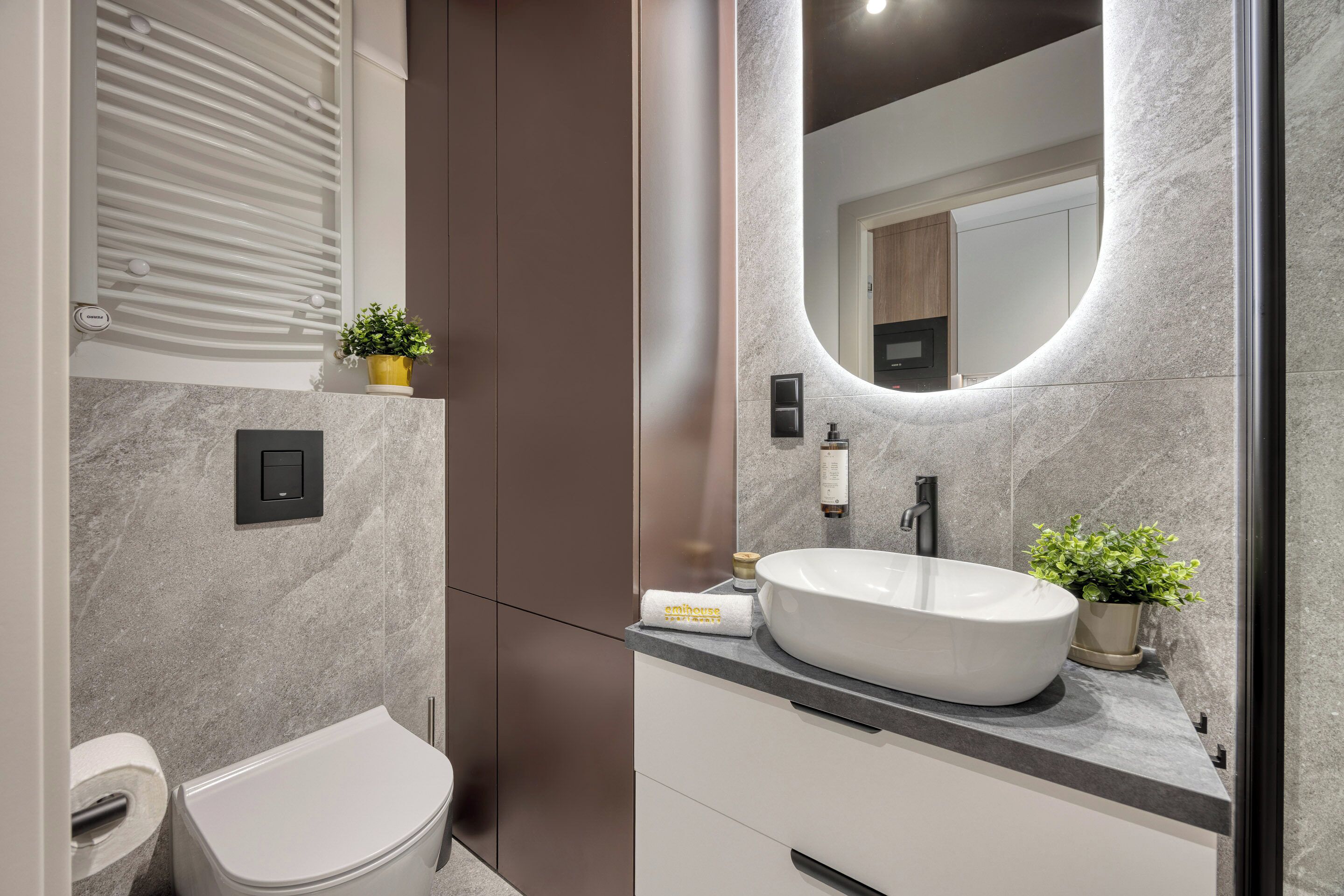A modern bathroom with a white sink, a mirror, and a toilet.