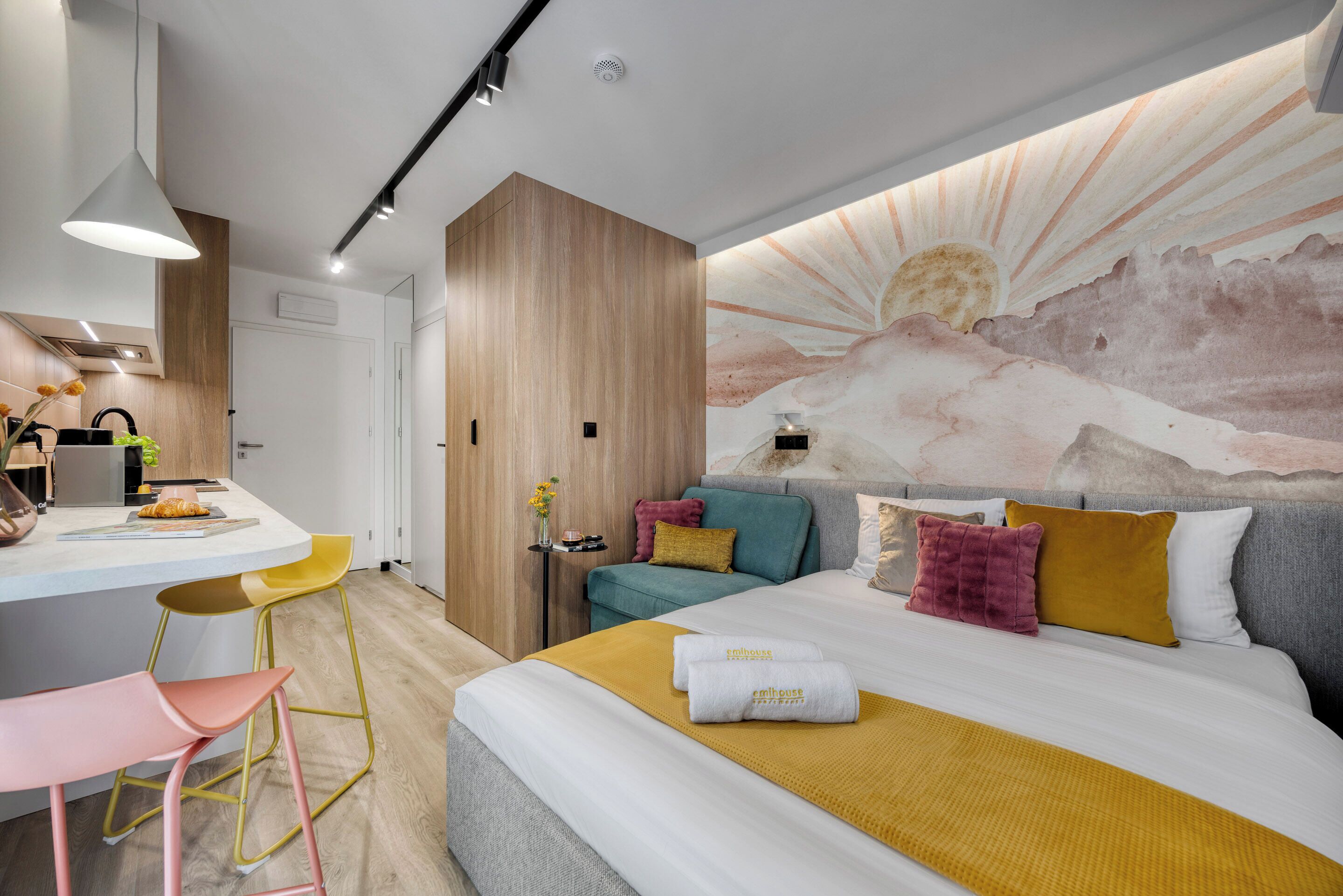 A modern hotel room with a bed, a desk, and a seating area.