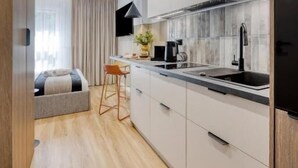 A modern kitchen with white cabinets, a black countertop, and a stainless steel sink. - Emihouse Rubikon Apartments (Rzeszów)