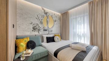 A bedroom with a bed, a sofa, a wall-mounted mirror, and a window with curtains.