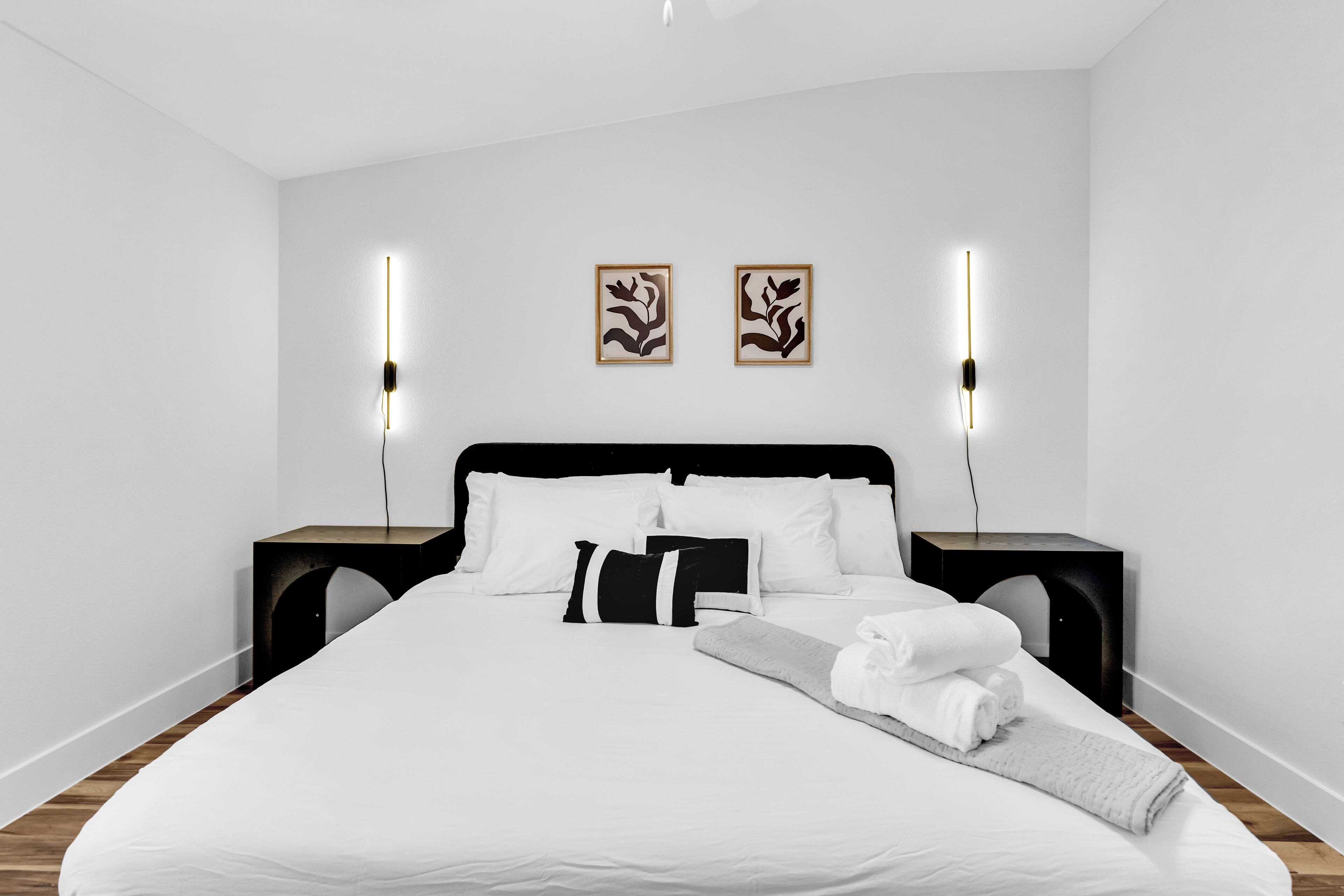 Een moderne slaapkamer met een groot bed, twee nachtkastjes en twee wandlampen.