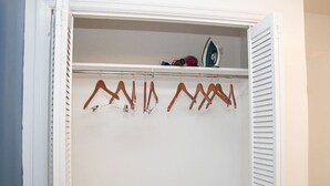 A closet with white doors and a hanging rod with clothes. - Cozy Retreat | 5 mins to Beach & Downtown (Nassau)
