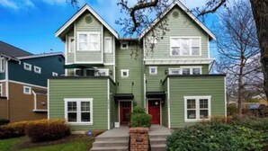 A two-story house with a green exterior, a red front door, and a brick entryway. - A marvelous 3-bedroom townhome in lovely Seattle  near children’s hospital (Seattle)