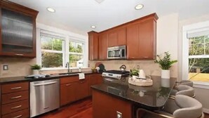 A modern kitchen with wooden cabinets, stainless steel appliances, and a central island with seating. - A marvelous 3-bedroom townhome in lovely Seattle  near children’s hospital (Seattle)