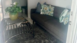 Ein Wohnzimmer mit einer Couch, einem Couchtisch, einer Pflanze und Wanddekoration.