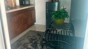 Eine kleine Küche mit Holzausstattung, einer Mikrowelle, einem Kühlschrank und einem Blumentopf.