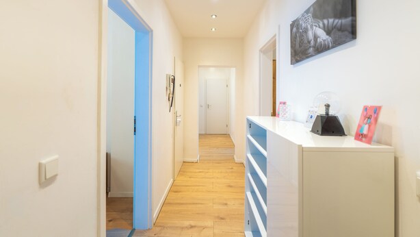 A hallway with a blue door, a white reception desk, and a framed picture on the wall.