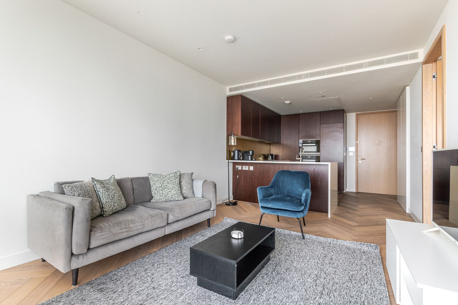 A modern living room with a grey sofa, a blue armchair, and a black coffee table.