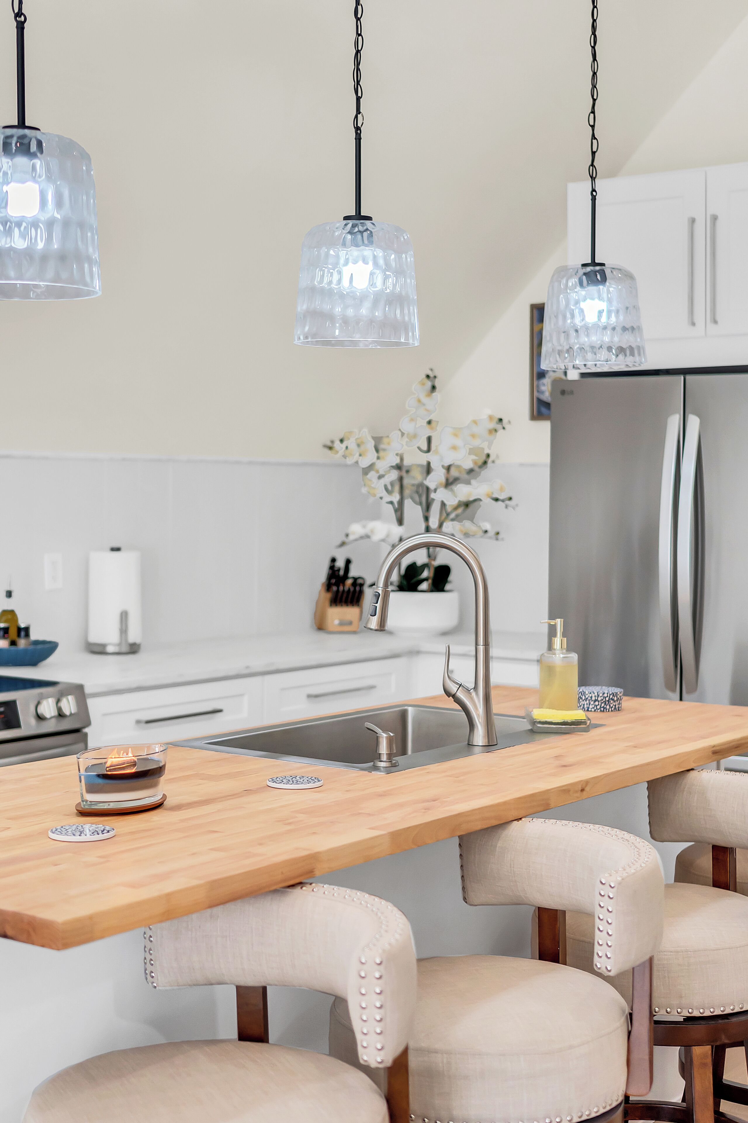 A modern kitchen with a wooden island, stainless steel appliances, and pendant lighting.