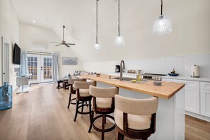 Une cuisine moderne dotée d’un îlot central, de tabourets de bar et de luminaires suspendus.