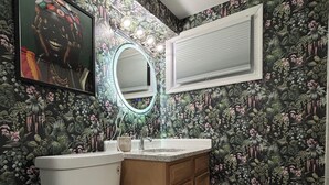 A bathroom with a toilet, sink, and mirror. The walls are covered with a floral wallpaper. - Getaway in Greater Navy Yard - 4BR/3BA -Sleeps 10+ (Washington)