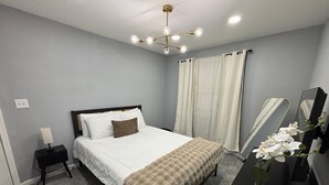 A bedroom with a bed, bedside table, lamp, mirror, and curtains. - Getaway in Greater Navy Yard - 4BR/3BA -Sleeps 10+ (Washington)