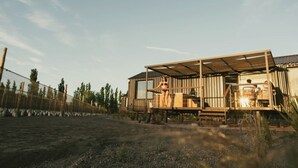 Una cabaña rústica con terraza de madera y zona de estar cubierta al aire libre.