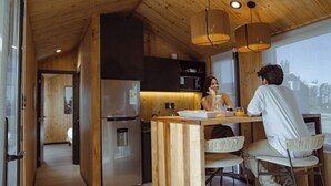 Una cocina moderna con armarios de madera, un refrigerador de acero inoxidable y una zona de bar con una banqueta.