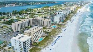Ein Küstenhotel mit mehreren Gebäuden, einem Strand mit Sonnenschirmen und Blick auf den Ozean.