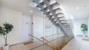Ein modernes Interieur mit einer Wendeltreppe, einem Blumentopf und einer Tür mit der Aufschrift '12'.