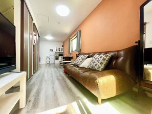 A compact living space with a sofa, a television, a kitchenette, and a dining area. - Fukusuke HARUKA Tsuruhashi 5mins walk JR Loop/Namba/USJ/ (tsuruhashi, ikuno ward, Osaka city)