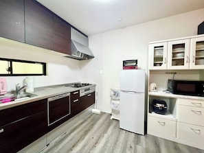 A modern kitchen with dark cabinets, a stainless steel countertop, a built-in dishwasher, a white refrigerator, and a microwave. - Fukusuke HARUKA Tsuruhashi 5mins walk JR Loop/Namba/USJ/ (tsuruhashi, ikuno ward, Osaka city)