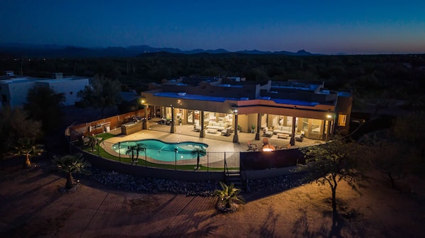 A modern house with a pool, outdoor seating, and a covered patio area.