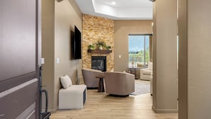 A modern living room with a fireplace, comfortable seating, and a large window offering a view.