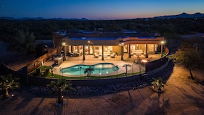A large house with a swimming pool, outdoor seating, and a view of the mountains.