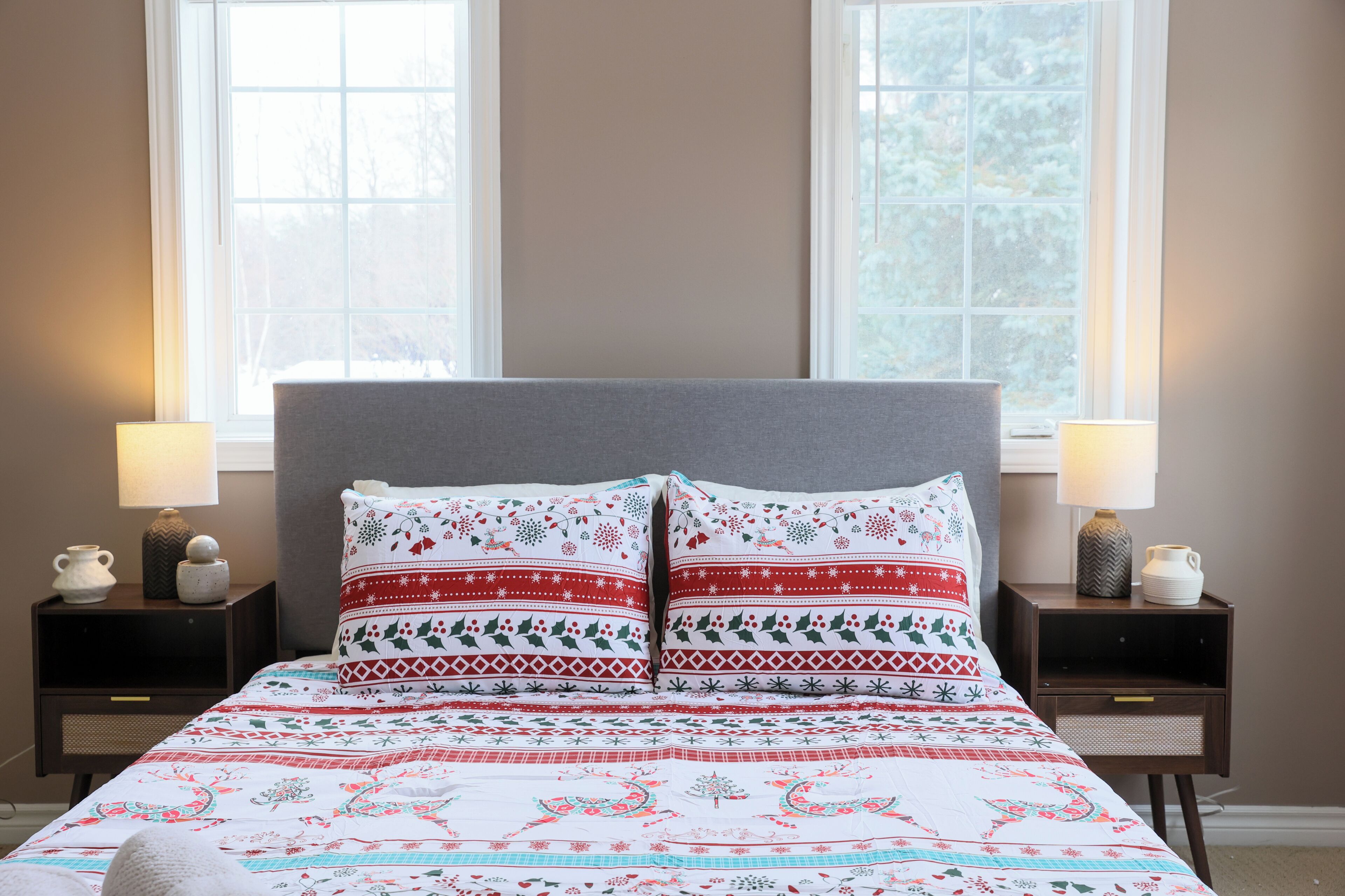 A bed with a patterned bedspread and two pillows, flanked by nightstands with lamps and decorative items.