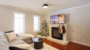 A living room with a fireplace, a Christmas tree, and a television.
