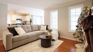 A living room with a beige sectional sofa, a round coffee table, and a Christmas tree.