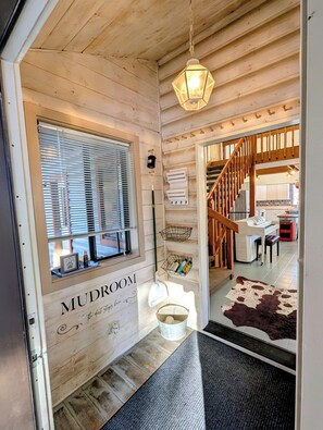 A wooden interior with a sign reading "MUDROOM," a wooden staircase, a piano, and a cowhide rug. - Welcome to The Hen House in Greer! Wraparound Porch, Movie Room & Coffee Bar (Greer)