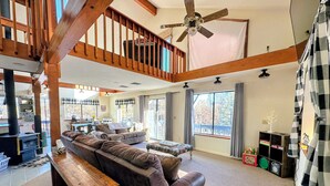 Un salon spacieux avec un grand canapé, un banc en bois et un ventilateur de plafond.