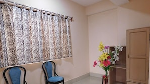 A room with two chairs, a cabinet, and a vase with flowers. - OS HOTEL HIDDEN FLOWER (Gangtok)