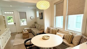 A modern kitchen with a round dining table, a built-in oven, and a hanging light fixture.