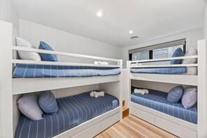 A room with bunk beds, each with a pillow and a blanket. - Riptide Lorne (Lorne)