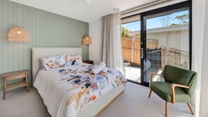 Ein Schlafzimmer mit Bett, Nachttischen, einem Sessel und Blick ins Freie.