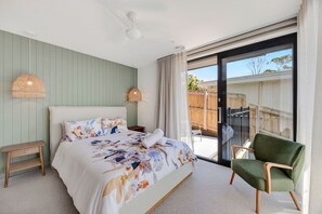 Ein Schlafzimmer mit Bett, Nachttischen, einem Sessel und Blick ins Freie.