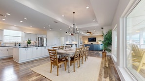 A spacious kitchen with a central island, wooden dining table, and chairs. - KD694 Private Heated Pool, Ocean Views (Port Aransas)