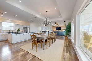 A spacious kitchen with a central island, wooden dining table, and chairs. - Private Heated Pool, Ocean Views, Golf Cart Included (Port Aransas)