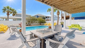 A covered outdoor area with a pool, white Adirondack chairs, and a picnic table. - KD694 Private Heated Pool, Ocean Views (Port Aransas)