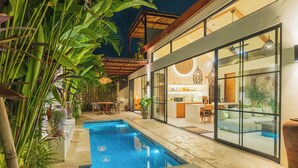 A modern house with a swimming pool, large windows, and a dining area. - Villa Rasa Rasa by Alfred in Bali (Cemagi)