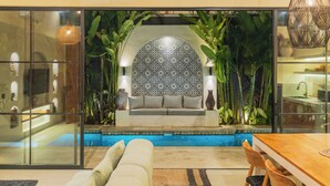 A modern interior with a pool, a sofa, and a dining area. - Villa Rasa Rasa by Alfred in Bali (Cemagi)